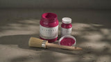 Two jars of Fusion Mineral Paint in Raspberry Alchemy, one open and one closed, shown with a brush.