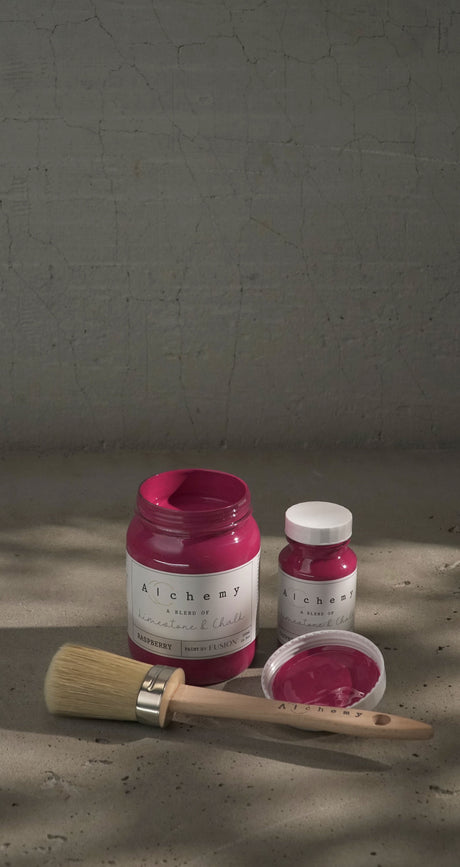 Three jars of Fusion Mineral Paint Raspberry Alchemy with a paintbrush displayed on concrete.