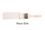 Brush with Fusion Mineral Paint Raw Silk, warm white acrylic paint, displayed on a plain white background.