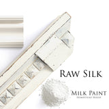 Wood molding dusted with white, labeled Homestead House Raw Silk Milk Paint.