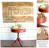 Red side table painted with Sweet Pickins Red Wagon Milk Paint, styled with books and a vase on top.