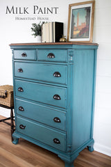 Six-drawer dresser painted Renfrew Blue Milk Paint by Homestead House, decor on top, wicker basket on chair nearby.