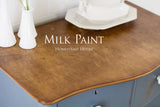 Wooden dresser in Homestead House Rideau Blue Milk Paint with brown top, topped with white vases and dishware.