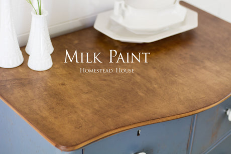 Wooden dresser in Homestead House Rideau Blue Milk Paint with brown top, topped with white vases and dishware.