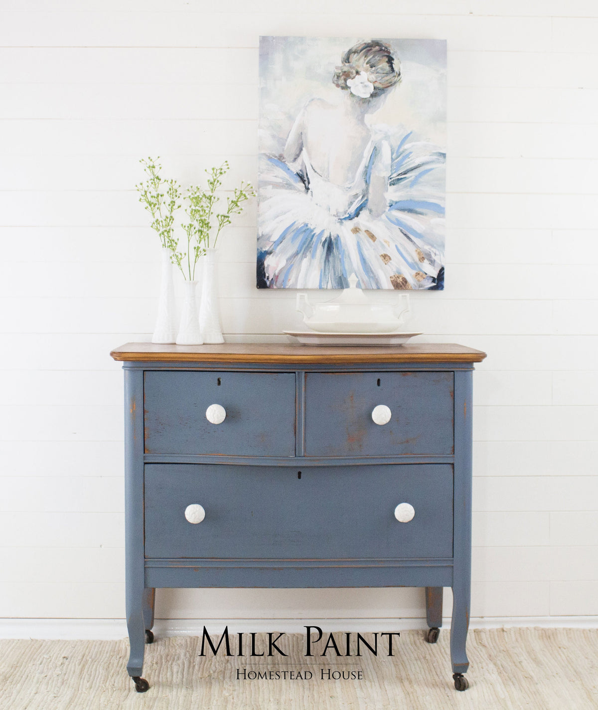 Dresser in Homestead House Rideau Blue Milk Paint with white knobs, vases on top, and ballerina painting above.