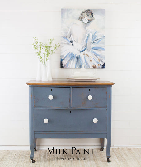 Dresser in Homestead House Rideau Blue Milk Paint with white knobs, vases on top, and ballerina painting above.