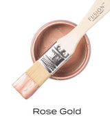 Paintbrush with Rose Gold Metallic Fusion Mineral Paint on a jar; text below reads “Rose Gold.”.