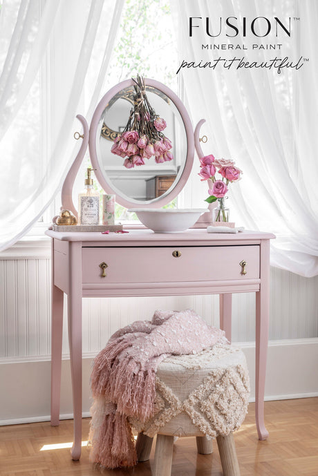Neutral pink vanity in Fusion Mineral Paint Rose Water by sheer curtains, with a textured stool nearby.