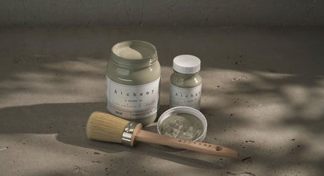 Sage Alchemy Paint by Fusion Mineral Paint open with brush, beside a jar and small bottle on concrete.