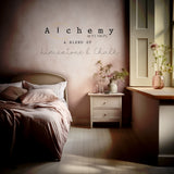 White bed with pink bedding, vases, and “Sandstone Alchemy Paint by Fusion” sign above nightstand in sunlit room.