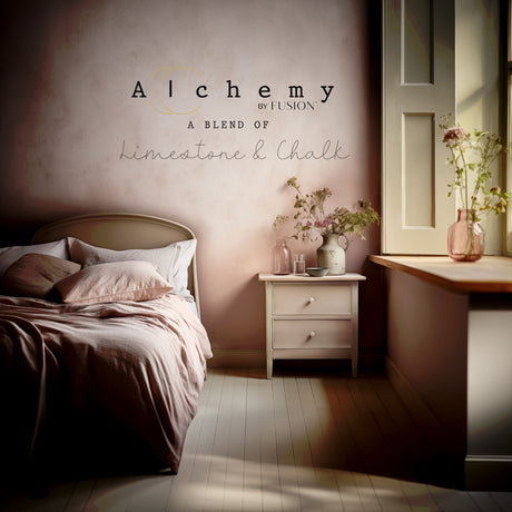 White bed with pink bedding, vases, and “Sandstone Alchemy Paint by Fusion” sign above nightstand in sunlit room.