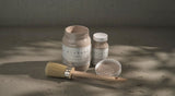 Three Sandstone Alchemy Paint by Fusion containers, one open with a brush, arranged on a textured surface.