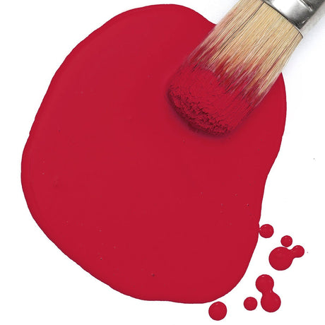 Paintbrush resting on Sangria Milk Paint by Fusion Mineral Paint, with paint drips on white background.