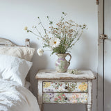 White bed next to rustic nightstand featuring I.O.D. Sarah Featon’s Botanicals Transfer and wildflowers in a vase.