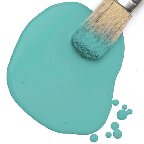 Paintbrush on teal Sea Glass Paint by Fusion Mineral Paint, shown with splatters on a white surface.