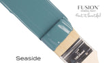 Paintbrush with Seaside Fusion Mineral Paint label and coastal blue bristles on a white background.