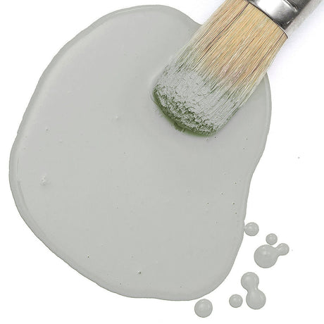 Brush on spilled Fusion Mineral Paint in Silver Screen with droplets on a white surface.