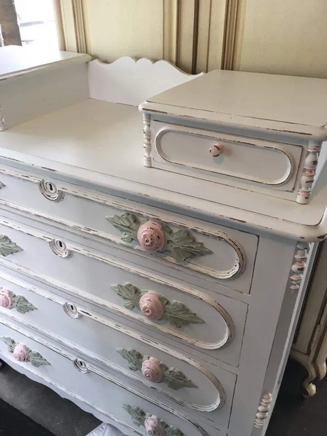 White vintage dresser restored with Miss Lillian’s Snowflake No-Wax Chock Paint, rose knobs, and green box.