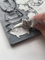 Hand lifting white casting from IOD Specimens Mould by Iron Orchid Designs on a white surface.