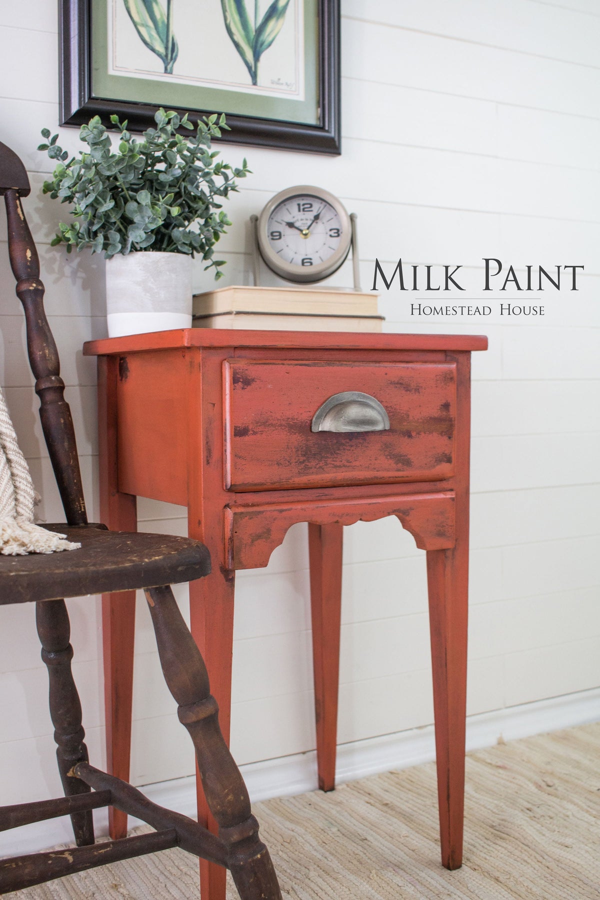 Red Homestead House Spice Milk Paint side table with books, clock, and plant placed next to a wooden chair.