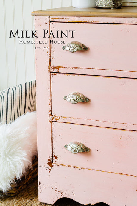 Pink dresser finished in Spring Blossom Milk Paint by Homestead House next to a striped pillow and faux fur rug.