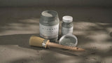 Three jars of Spruce Alchemy Paint by Fusion Mineral Paint with a paintbrush, one jar and brush open.