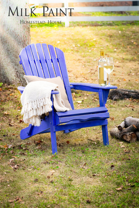 Blue Adirondack chair painted with Homestead House St-Laurent Blue Milk Paint, shown with wine and a blanket.