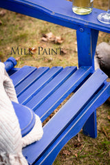 Blue chair in St-Laurent Blue Milk Paint by Homestead House, paired with gray blanket, wine bottle, and glass.