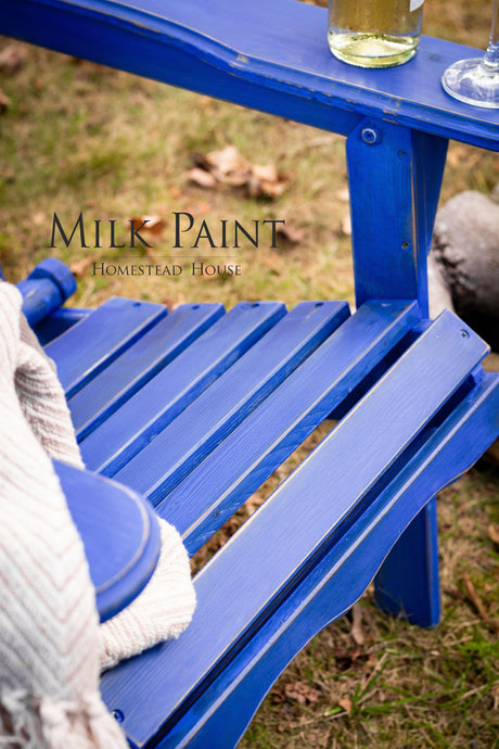 Blue chair in St-Laurent Blue Milk Paint by Homestead House, paired with gray blanket, wine bottle, and glass.