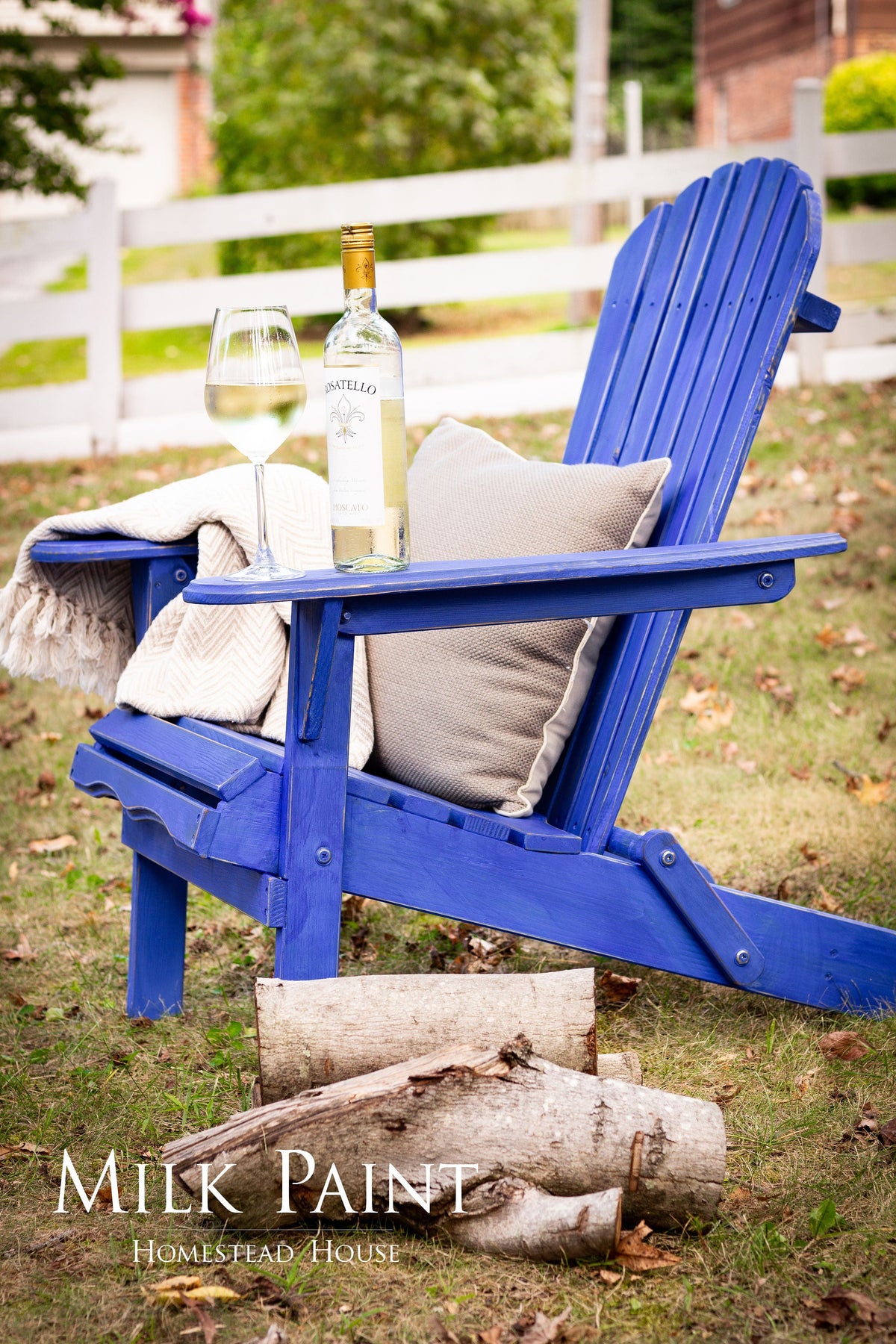 Blue Adirondack chair in St-Laurent Blue Milk Paint by Homestead House with a wine bottle and glass on the seat.