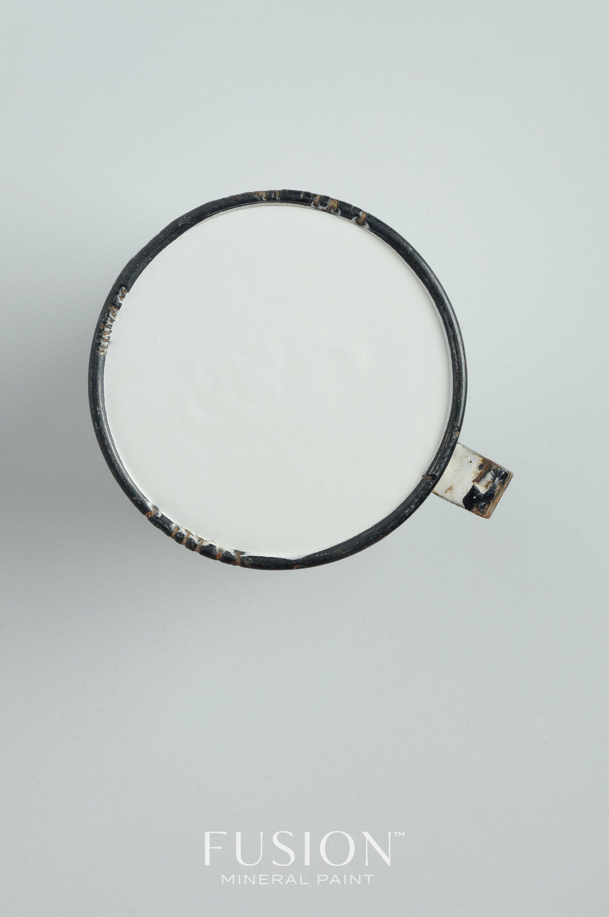 Black mug with white liquid, placed on white surface; Sterling Fusion Mineral Paint in Sterling color shown below.