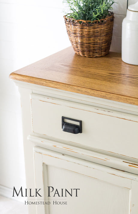 Cream Homestead House Stone Fence Milk Paint cabinet with wood top, black pull, plant basket, and white jar.