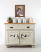 Cream cabinet with decor; painting above displays text “Stone Fence Milk Paint by Homestead House.”.