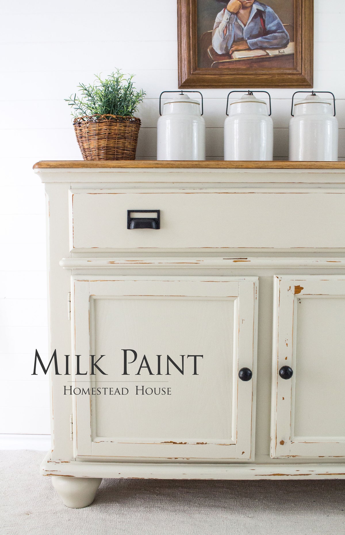 Cream distressed cabinet with jars, plant basket, and art. Text: Stone Fence Milk Paint by Homestead House.