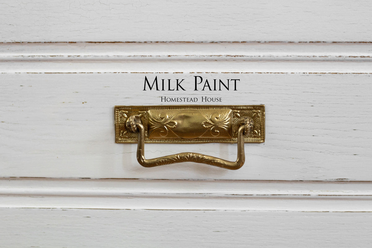 Brass drawer pull on Sturbridge White Milk Paint by Homestead House, text displayed above the handle.