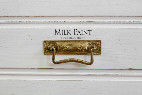 Brass drawer pull on Sturbridge White Milk Paint by Homestead House, text displayed above the handle.
