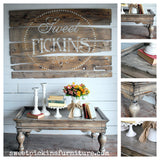 Coffee table with flowers and books beneath a Suitcase – Sweet Pickins Milk Paint sign by Old Fashioned Milk Paint.