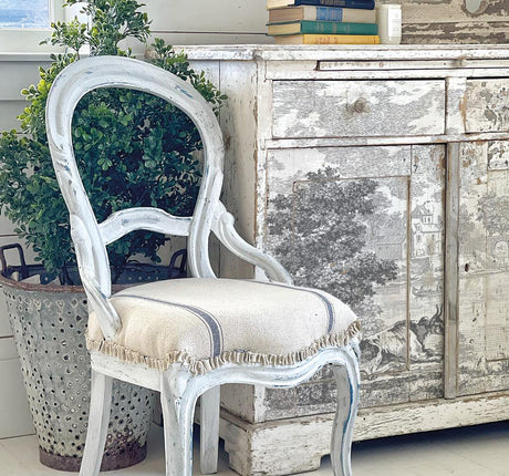 Distressed white chair beside cabinet featuring I.O.D. Summer Villa Paint Inlay by Iron Orchid Designs.