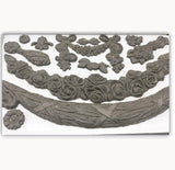 Ornate clay shapes created with IOD Swags Mould displayed on a white surface.