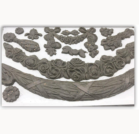 Ornate clay shapes created with IOD Swags Mould displayed on a white surface.