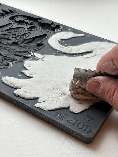 Hand pressing white clay into I.O.D. Swans Mould by Iron Orchid Designs featuring swan pattern.