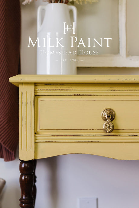 Yellow Swedish Yellow Milk Paint drawer by Homestead House, brass handle, wood legs, white vase on top.