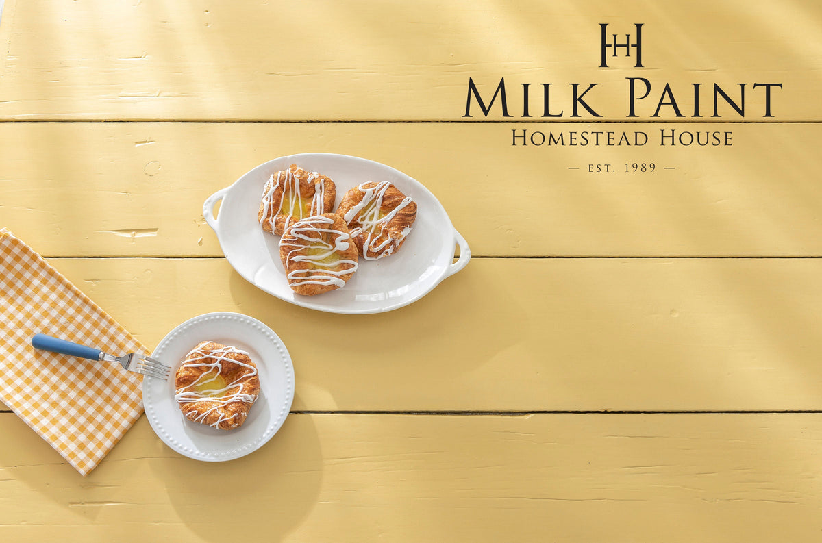 Three pastries on white plates displayed on a table painted in Homestead House Swedish Yellow Milk Paint.