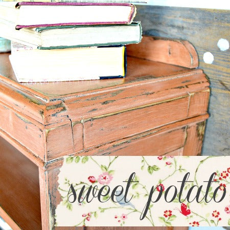 Vintage nightstand with stacked books, floral fabric, and cursive text, finished in Sweet Potato Milk Paint.
