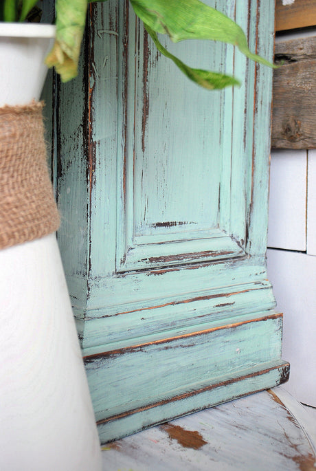 Distressed blue cabinet in Sweetie Jane by Old Fashioned Milk Paint next to burlap-wrapped white vase.