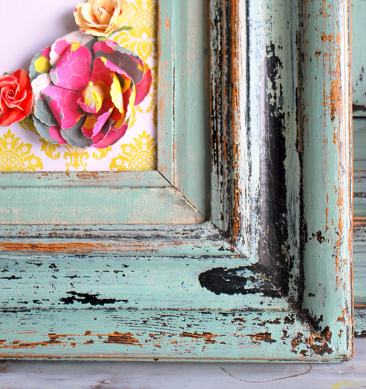 Distressed Sweetie Jane frame by Old Fashioned Milk Paint with paper flowers on a yellow background.