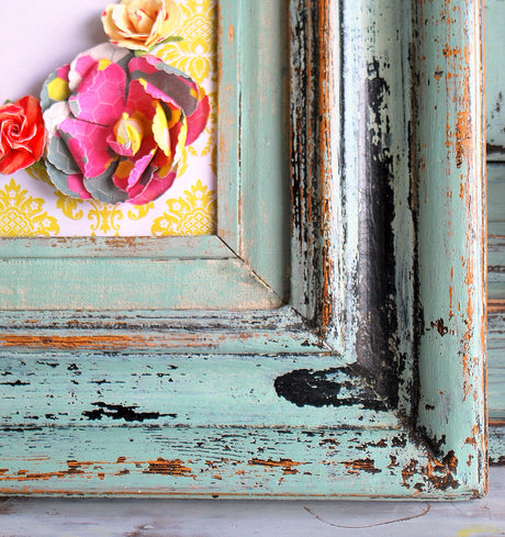 Distressed Sweetie Jane frame by Old Fashioned Milk Paint with paper flowers on a yellow background.