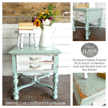 Distressed mint-green table in Sweetie Jane paint with white drawers, accompanied by chair, books, and flowers.