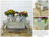 Coffee table painted Sweetie Jane by Old Fashioned Milk Paint with three metal vases of colorful flowers on top.