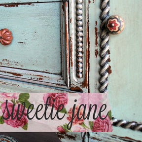 Distressed teal furniture finished in Sweetie Jane, with ornate knobs and floral accents over pink rose detailing.